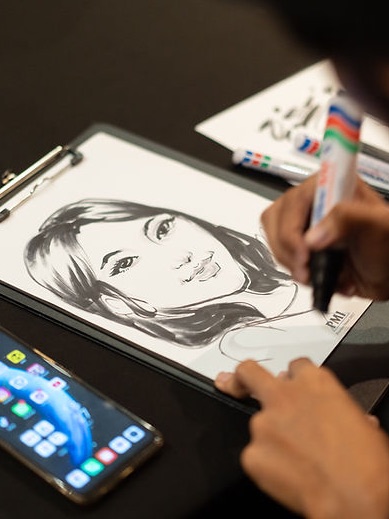 A caricature artist drawing a guest’s portrait by hand